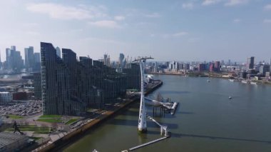 Thames Nehri ile Londra 'nın havadan görünüşü, solda O2 Arena ve arkada Canary Wharf. Tekneler ve feribotlar nehir boyunca hareket eder..