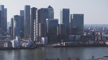 Londra 'nın Kanarya Rıhtımı' nın gökyüzü manzarası yüksek binalar, Thames Nehri ön planda ve Çömlek belli belirsiz görünür..