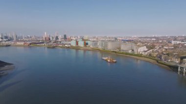 Modern binalar Thames Nehri ile Londra 'nın nehir kenarının havadan görünüşü, kenetlenmiş gemiler, yüksek ve orta yükselen yapılardan oluşan bir siluet..