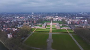 Kensington Sarayı 'nın ve Londra' daki bahçelerinin hava manzarasında yeşil çimenler, ağaç çizgili yollar ve arka planda kentsel ufuk çizgisi yer alıyor..