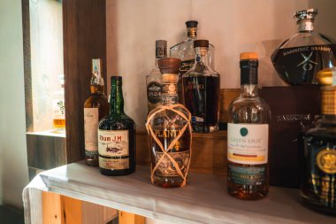 İtalyan Alpleri 'ndeki lüks bir otel barında ahşap raflarda Rhum J.M ve Plantation da dahil olmak üzere rom, viski ve brendi şişeleri koleksiyonu..