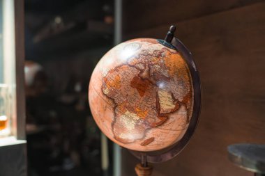 Afrika, Avrupa ve Ortadoğu 'nun detaylı haritasına sahip klasik tarz bir küre. Kapalı alandaki ahşap bir duvara karşı ahşap bir standa monte edilmiş..