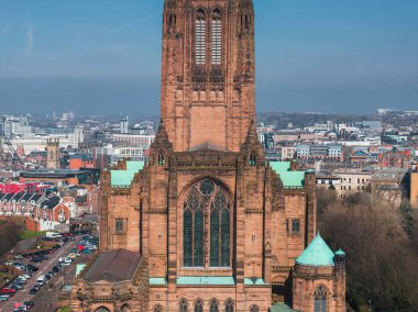 Liverpool Katedralleri Gotik mimari, kumtaşı yapı ve yeşil bakır çatılar berrak mavi gökyüzü altındaki kentsel binaların arasında göze çarpıyor..