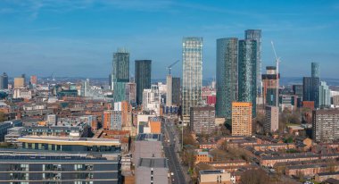 Manchester, İngiltere 'nin hava görüntüsü, modern gökdelenleri, inşaat vinçlerini ve güneşli bir günde tarihi ve çağdaş binaların bir karışımını gösteriyor..
