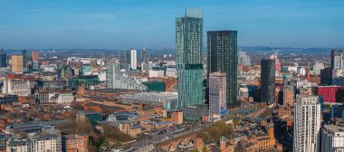 Beetham Tower, modern gökdelenler, tarihi mimari, demiryolu kemerleri ve açık gökyüzü altındaki uzak tepelerin yer aldığı Manchester, İngiltere 'nin hava manzarası.