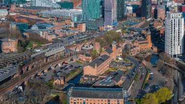Manchester, İngiltere 'nin hava görüntüleri, güneşli bir günde Castlefield' ın kırmızı tuğla binalarını, kanallarını, viyakanallarını, gökdelenlerini, yolları, köprülerini ve yeşil alanları gösteriyor..