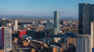 Manchester, İngiltere 'nin hava manzarası, modern gökdelenlerin, karışık mimarinin ve güneşli bir günde arka planda dönen tepelerin sergilenmesi.