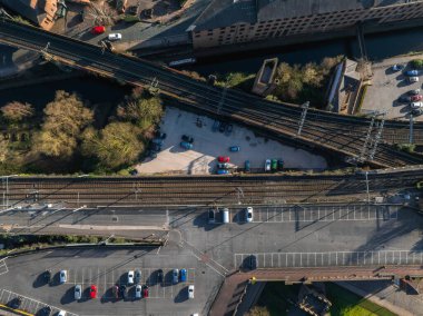 Parlak güneş ışığı altında Manchester, İngiltere 'de kesişen tren yolları, bir kanal, otoparklar ve endüstriyel binaların hava görüntüsü..