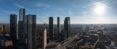 Gökdelenlerle güneşli bir günde Manchester, İngiltere 'nin hava manzarası, inşaat halindeki bir bina, yollar, bir kanal ve karışık mimari üzerinde bir vinç..