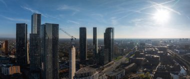 Gökdelenlerle güneşli bir günde Manchester, İngiltere 'nin hava manzarası, inşaat halindeki bir bina, yollar, bir kanal ve karışık mimari üzerinde bir vinç..