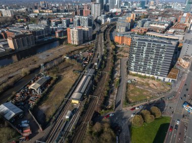 Manchester, İngiltere 'nin hava manzarası, güneşli bir günde demiryolu rayları, bir kanal, modern gökdelenler, tarihi binalar ve yoğun bir şehir düzeni..