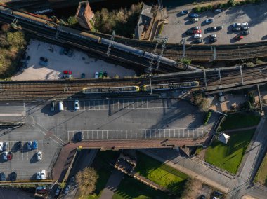 Manchester, İngiltere 'deki bir otoparktan geçen tren, park halindeki arabalar, köprüler, yeşil alanlar ve görülebilir patikalar..
