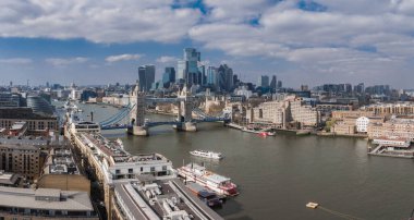 Thames Nehri 'nin üzerindeki Tower Bridge' in tarihi ve modern mimarisi ve parçalı bulutlu gökdelenler altındaki Londra şehrinin havadan görüntüsü..
