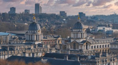 Greenwich, Londra 'daki eski Kraliyet Donanma Koleji' nin kubbeli binaları klasik mimariyle göze çarpıyor, modern bir şehir siluetine karşı diziliyor..