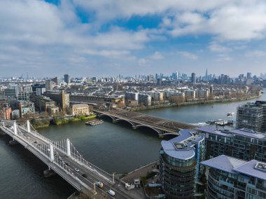 Thames Nehri, Albert Köprüsü, Chelsea Köprüsü ve Çömlek 'ün yer aldığı Londra' nın hava manzarası. Modern binalar ve parçalı bulutlu gökyüzü görülebilir.