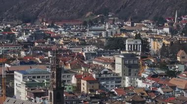 İtalya 'nın Bolzano kentinin havadan görünüşü Gotik tarzı katedrali, kırmızı çatılı binaları, inşaat vinçlerini, etrafındaki tepeleri ve dağları vurguluyor..