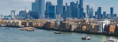 Londra Kanarya Rıhtımı 'nın canlı hava manzarası modern gökdelenler Thames nehri, tarihi tuğla binalar ve sudaki tekneler..