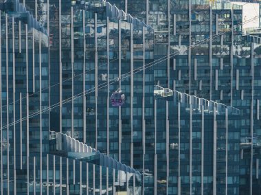Sivri uçlu cam cepheli modern bir bina ve Emirates Hava Hattı 'ndan bir teleferik Londra şehir merkezinde havada asılı duruyor..