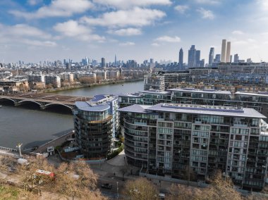 Londra 'nın havadan görünüşü Thames Nehri' ni, modern eğimli konut binalarını, bir köprüyü, Çömlek 'ü ve Battersea Enerji İstasyonu bacalarını gösteriyor..