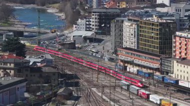 İtalya 'nın Bolzano kentinin havadan görünüşü trenlerin bir tren istasyonunda, modern ve tarihi binalarda ve görünür inşaat faaliyetlerinde hareket ettiğini gösteriyor..