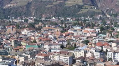 Bolzano, İtalya 'nın havacılık panosu, modern ve geleneksel binaların bir karışımını, bir kilise kulesini, tarihi bir yapıyı ve etrafındaki dağları gösteriyor..