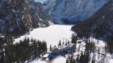 Kuzey İtalya 'da kış boyunca Braies Gölü' nün havadan görünüşü, donmuş bir yüzey, uçurumlar, yemyeşil ormanlar ve dağınık figürlerle karla kaplı..