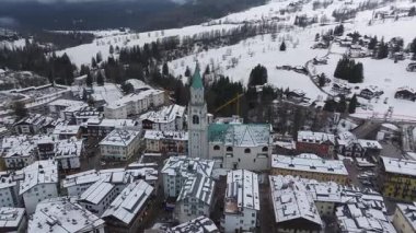 Kışın Cortina d 'Ampezzo' nun havalimanında, Basilica Minore 'un yeşil kulesi, karla kaplı tarlaları, ormanları ve görünür bir inşaat vinci yer alıyor..