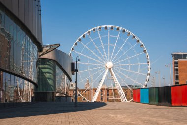 Liverpool Rıhtımı 'nda Liverpool Tekerleği, MandS Bank Arena' nın cam cephesi, tarihi tuğla binalar ve temiz bir gökyüzünün altında asfalt bir yol yer almaktadır..