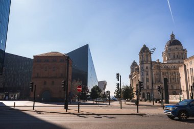 Liverpool 'da kubbeli Liverpool Limanı, modern cam Liverpool Müzesi ve açık gökyüzü altında kırmızı tuğladan bir yapı bulunan sessiz bir cadde..