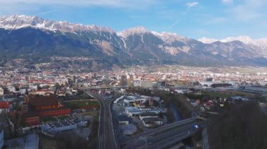 Innsbruck, Avusturya 'nın hava manzarası, Nordkette dağlarını, şehir mimarisini, yolları, bir köprüyü ve pürüzsüz yüzey hareketini gösteriyor.