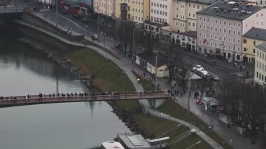 Salzburg, Avusturya hava görüntüsü, Salzach Nehri üzerinde hareket eden araçlar, yayalar ve kentsel çevreyle iki köprü gösteriyor..