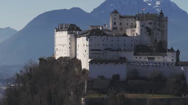 Avusturya 'nın Salzburg kentindeki Hohensalzburg Kalesi' nin havadan görünüşü. Arka planda ortaçağ mimarisi, kış ağaçları ve karlı dağlar var..