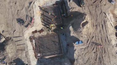 Çelik yapıları, makineleri, kırmızı bariyerleri ve toprak izleri olan Riga şantiyesindeki yüksek görüş alanındaki işçilerin hava görüntüsü..