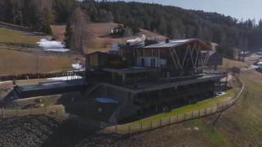 Güney Tyrol, İtalya 'da bir tepe otelinin pürüzsüz hava görüntüsü. Pürüzsüz bir tasarımı, dumanı tüten bir sonsuz havuzu ve arka planda Dolomite dağları var..