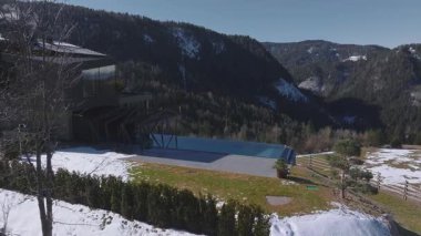 Güney Tyrol, İtalya 'da modern bir otel. Sonsuz havuzu, tozlu tepeleri, sık ormanları ve karla kaplı çitli bir çayırı var..