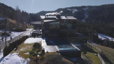 Güney Tyrol, İtalya 'da modern otel, sonsuz havuzlu, karla kaplı zemin, ormanlı tepeler ve arka planda Dolomite dağ zirveleri.