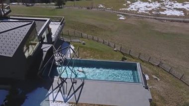 Çatı eğimli, sonsuz havuzlu, Dolomite dağları, karlı tepeler, ormanlar ve kayak merkezi olan modern bir otelin yavaş havası..