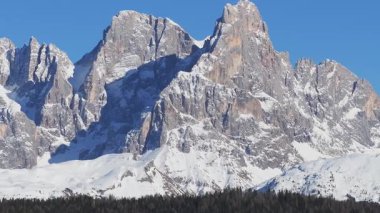 İtalya 'nın güney Tyrol kentindeki Dolomite dağ sırasının açık mavi gökyüzünün altında karla kaplı zirveleri görülüyor. Yavaş çekim veya yakınlaştırma engebeli araziyi vurgular.