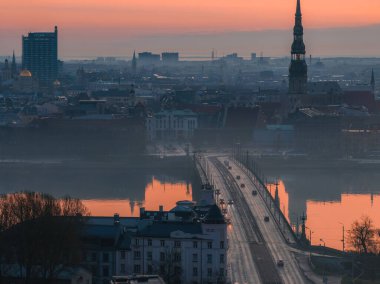 Riga, Letonya 'da sakin bir gün doğumu, St. Peter Kilisesi kulesi, bir köprüsü olan Daugava Nehri ve tarihi ve modern binaların karışımı..