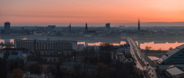 Riga, Letonya üzerinde sakin bir gün doğumu, St. Peter Kilisesi, Riga Katedrali, Vansu Köprüsü ve Daugava Nehri kenarındaki Ulusal Kütüphane.