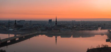 Riga, Letonya 'da sakin bir gün doğumu, Aziz Peter Kilisesi kulesi, tarihi binalar, Daugava Nehri üzerinde bir köprü ve sabah sisi..