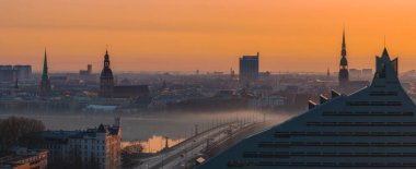 Riga, Letonya üzerinde sakin bir gün doğumu, St. Peter Kilisesi, Riga Katedrali, Ulusal Kütüphane, ve bir köprüsü olan sisli Daugava Nehri.