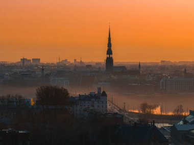 Riga, Letonya 'da sakin bir gün doğumu, St. Peter Kilisesi kulesi, Daugava Nehri, tarihi çatılar ve manzarayı güçlendiren hafif bir sis..