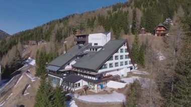Dolomitlerdeki Nockalm Oteli 'nin havadan görünüşü. Dağ yamaçlarındaki yeşil ormanlar, kar tarlaları ve geleneksel dağ tebeşirleriyle çevrili..