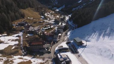 Dolomitler 'de karlı yamaçlar, ormanlar, çimenli alanlar ve dolambaçlı yollarla çevrili lüks bir otelin havadan görünüşü. Kamera sorunsuz çalışıyor.