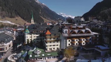 Avusturya 'nın Ischgl kentinin havadan görünüşü, Alp mimarisini gösteriyor, yeşil bir kilise, hareketli sokaklar ve arka planda karla kaplı dağlar..