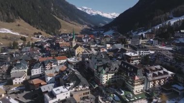 Avusturya 'nın Ischgl kentinin havadan görünüşü, Alp mimarisini gösteriyor, yeşil bir kilise, karla kaplı dağlar, ormanlar ve karlı açık alanlar..