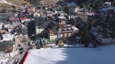 Avusturya 'nın Ischgl kentinin havadan görünüşü, yeşil bir kilise, dağlık bir mimari, lüks oteller ve dağlık bir alanda karla kaplanmış çatılar.