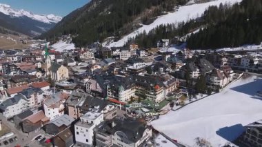 Avusturya 'nın Ischgl şehrinde, Alp mimarisini gösteren düz bir üstgeçit, yeşil bir kilise, lüks oteller, kar bantları ve çevre ormanları..