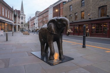 Londra 'da sakin bir yaya caddesinde, tuğla ve taş binalarla çevrili, arkasında kilise kulesi olan bronz bir fil heykeli..